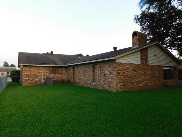 rear view of house with a yard and central AC