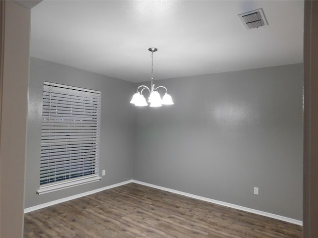 unfurnished room with a chandelier and dark hardwood / wood-style flooring