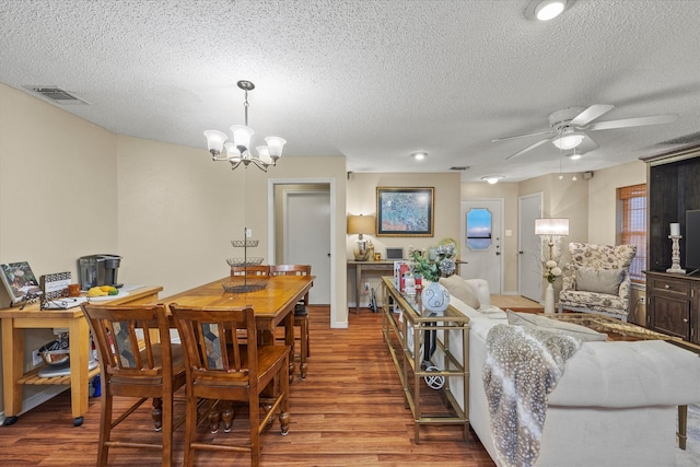 dining space with a textured ceiling, ceiling fan with notable chandelier, and hardwood / wood-style floors