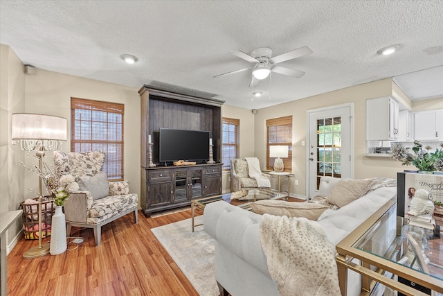 living room with a textured ceiling, ceiling fan, plenty of natural light, and light hardwood / wood-style flooring