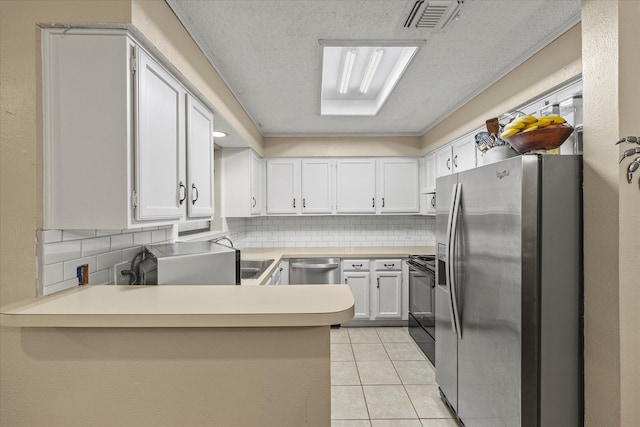 kitchen featuring light tile patterned flooring, tasteful backsplash, kitchen peninsula, appliances with stainless steel finishes, and white cabinetry