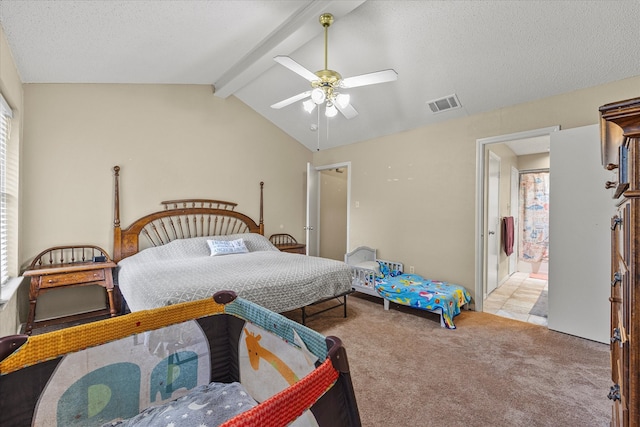 bedroom with ceiling fan, vaulted ceiling with beams, connected bathroom, a textured ceiling, and light colored carpet