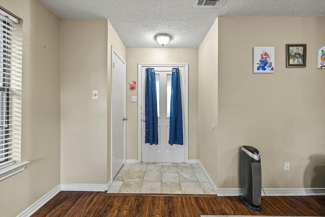 entryway with wood-type flooring and a textured ceiling