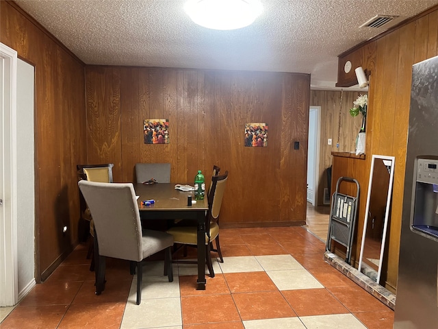 dining area featuring light tile patterned floors and wooden walls