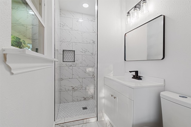 bathroom featuring vanity, toilet, and tiled shower