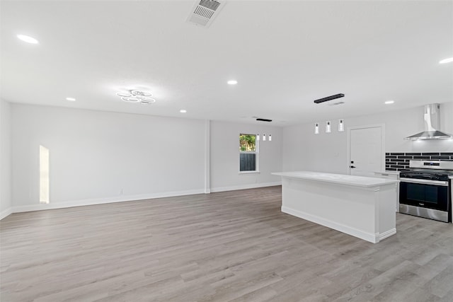 kitchen featuring a center island, stainless steel range, pendant lighting, light hardwood / wood-style floors, and wall chimney range hood