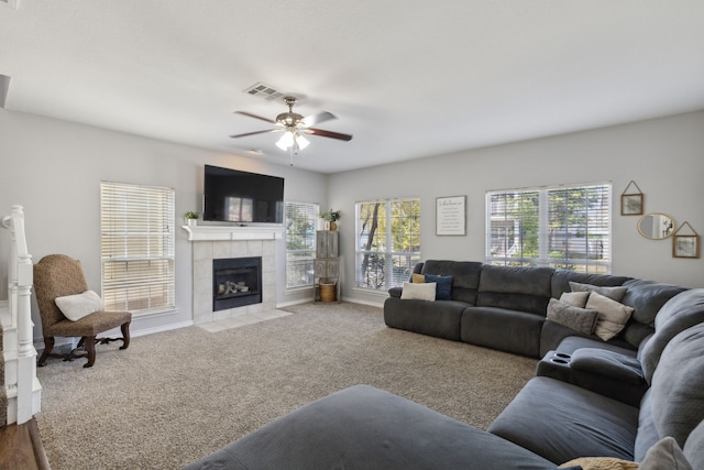 carpeted living room with a tile fireplace and ceiling fan