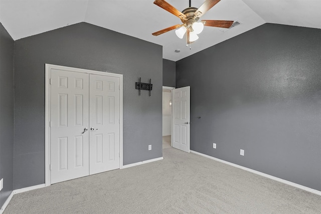 unfurnished bedroom with a closet, vaulted ceiling, light carpet, and ceiling fan