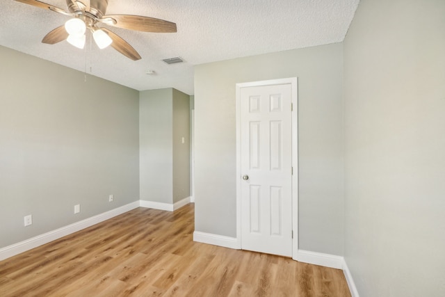 empty room with light wood-type flooring, ceiling fan, and a textured ceiling