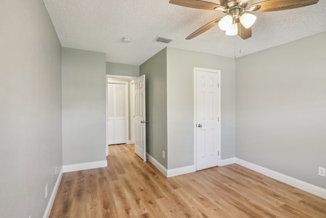 unfurnished bedroom featuring light wood-type flooring, ceiling fan, and a textured ceiling