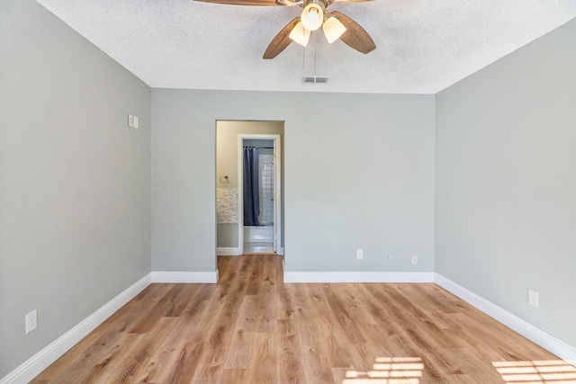 empty room featuring ceiling fan, light hardwood / wood-style flooring, and a textured ceiling