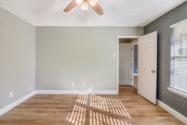 empty room with ceiling fan, light hardwood / wood-style floors, and a textured ceiling