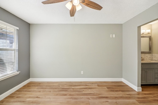 unfurnished room with ceiling fan, a textured ceiling, light hardwood / wood-style flooring, and sink