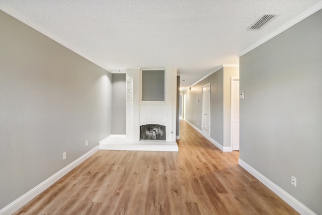 unfurnished living room featuring a brick fireplace, light hardwood / wood-style floors, ornamental molding, and a textured ceiling