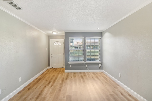 foyer featuring light wood-type flooring, crown molding, and a textured ceiling