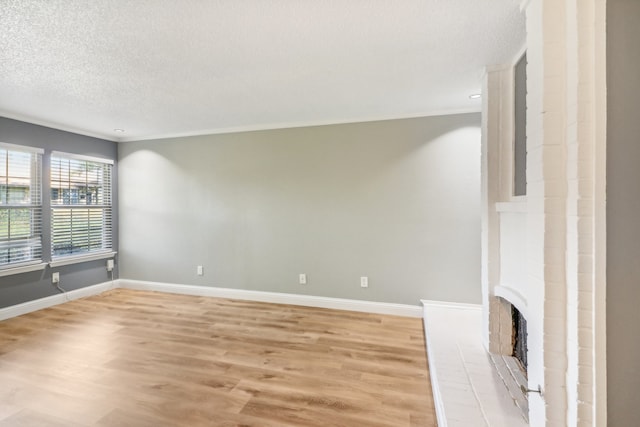 unfurnished living room with a fireplace, ornamental molding, light hardwood / wood-style flooring, and a textured ceiling