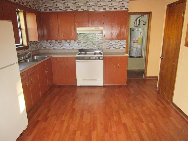 kitchen featuring water heater, sink, white appliances, and tasteful backsplash