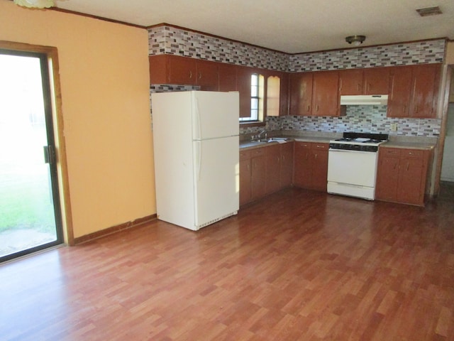 kitchen featuring white appliances, sink, light hardwood / wood-style floors, and backsplash