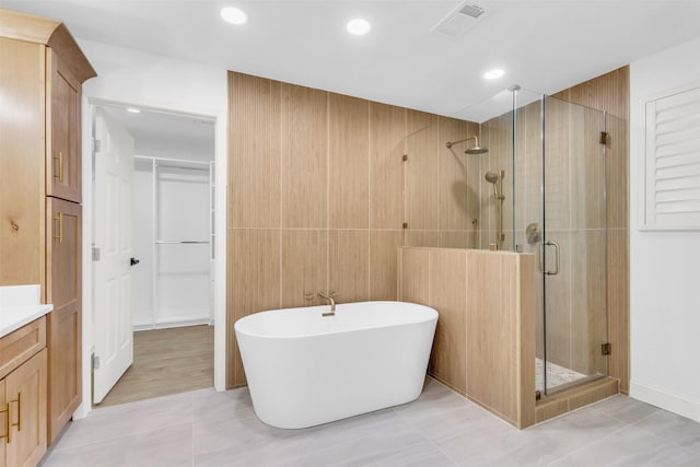 bathroom featuring a shower stall, tile patterned floors, a freestanding bath, vanity, and a closet