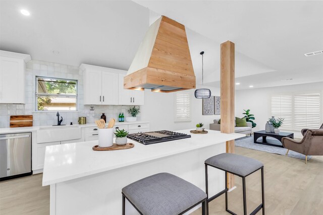 kitchen featuring gas cooktop, visible vents, dishwasher, light countertops, and premium range hood