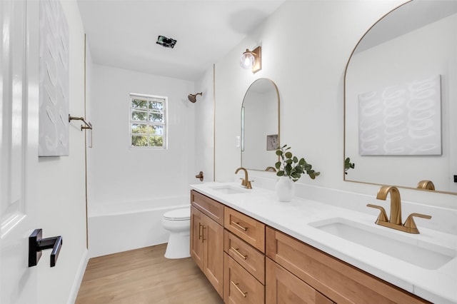 bathroom featuring double vanity, wood finished floors, toilet, and a sink