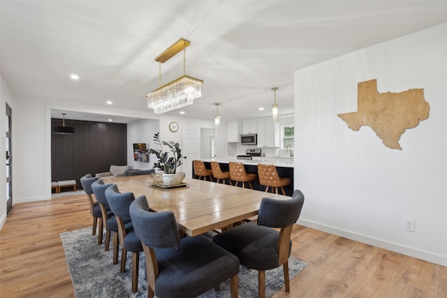 dining area featuring a chandelier, sink, and light hardwood / wood-style floors