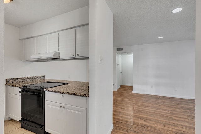 kitchen featuring dark stone countertops, black range with electric stovetop, white cabinetry, a textured ceiling, and light hardwood / wood-style floors