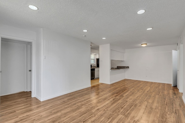 unfurnished living room with light hardwood / wood-style floors and a textured ceiling