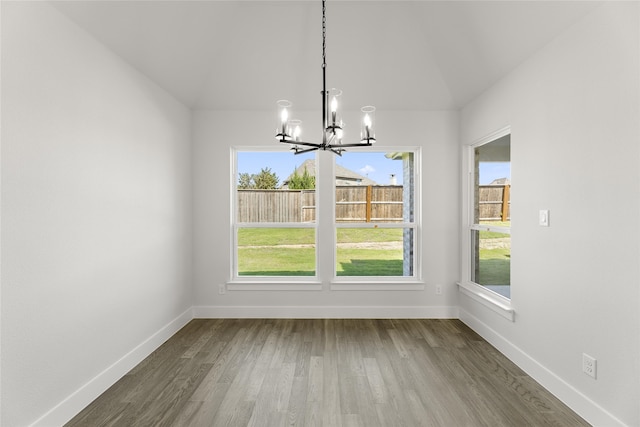 unfurnished dining area with a notable chandelier and wood-type flooring