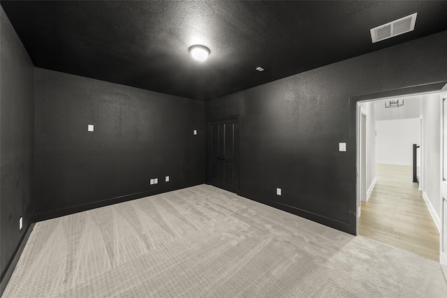 empty room with a textured ceiling and light colored carpet