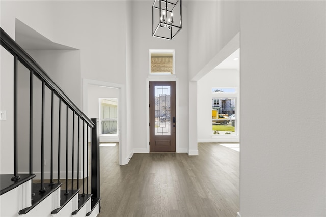 entrance foyer featuring a towering ceiling, a chandelier, and wood-type flooring