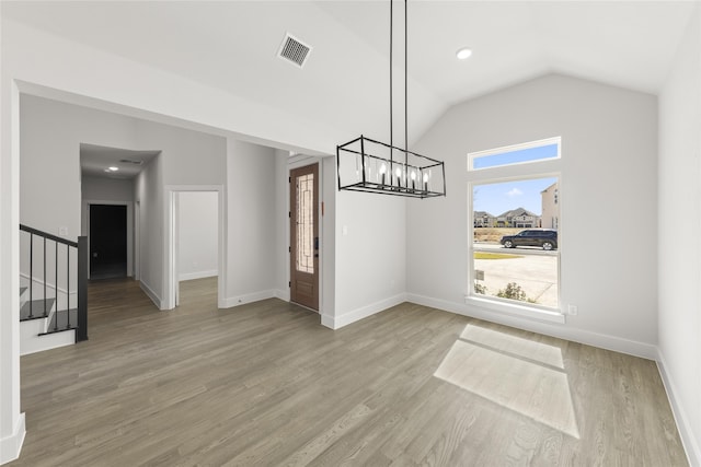 unfurnished dining area featuring vaulted ceiling, light hardwood / wood-style flooring, and an inviting chandelier