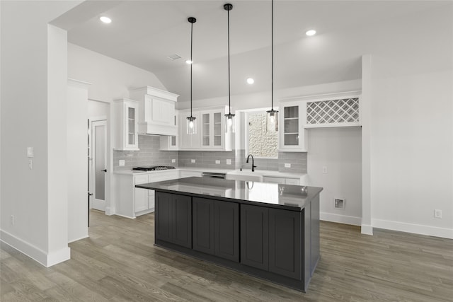 kitchen featuring hardwood / wood-style floors, tasteful backsplash, a kitchen island, white cabinetry, and decorative light fixtures