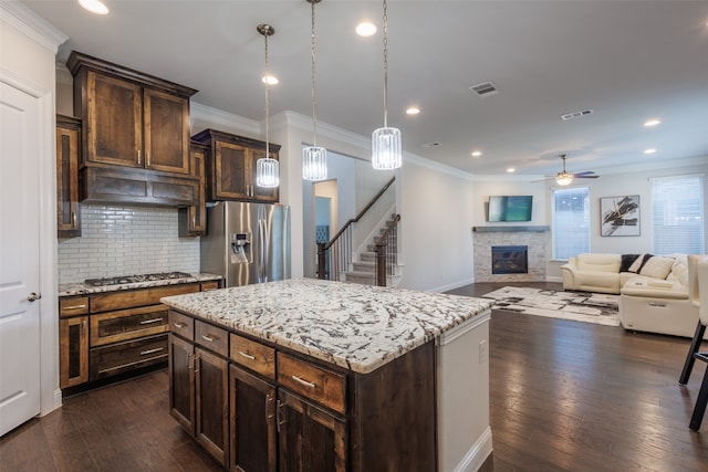 kitchen featuring appliances with stainless steel finishes, ornamental molding, a center island, and dark hardwood / wood-style floors