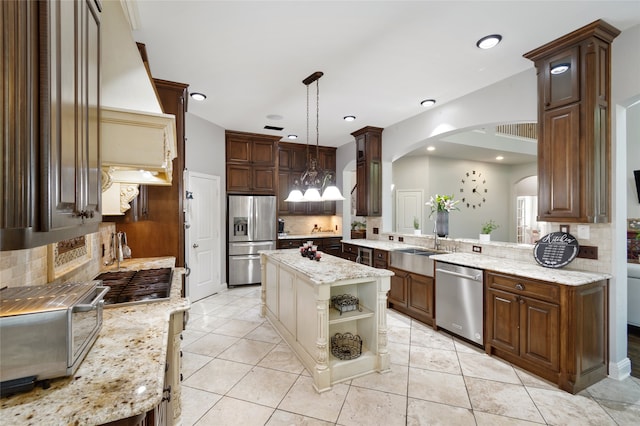 kitchen with a center island, kitchen peninsula, stainless steel appliances, decorative light fixtures, and a notable chandelier