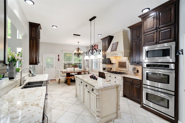 kitchen featuring light tile patterned floors, custom range hood, sink, a notable chandelier, and decorative light fixtures