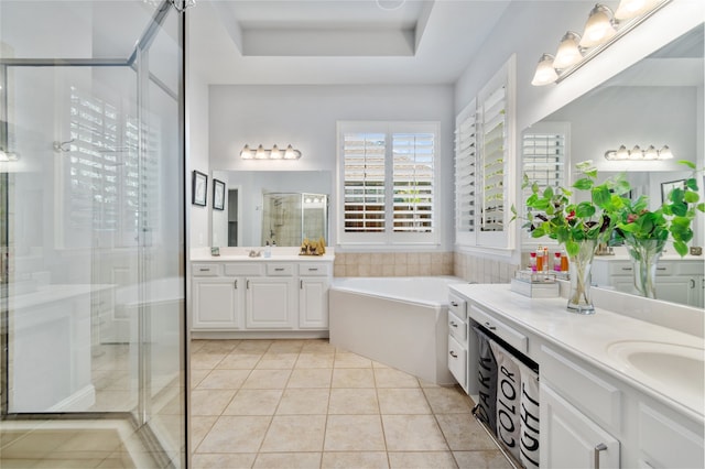 bathroom featuring vanity, a tray ceiling, separate shower and tub, and tile patterned flooring