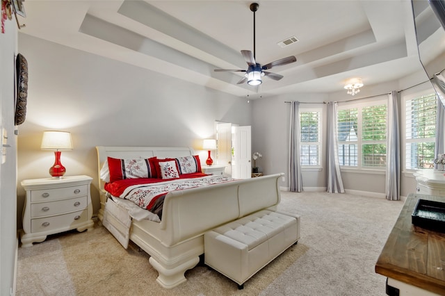 carpeted bedroom featuring ceiling fan and a raised ceiling