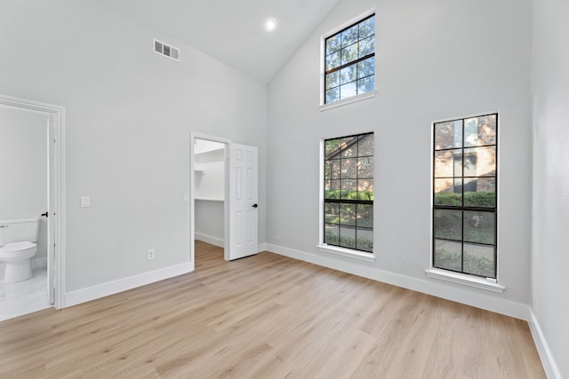 spare room featuring light hardwood / wood-style flooring, high vaulted ceiling, and plenty of natural light