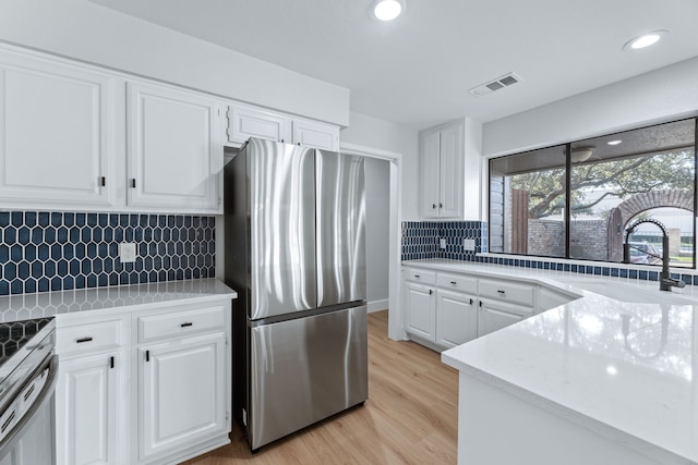 kitchen with light hardwood / wood-style floors, appliances with stainless steel finishes, sink, and white cabinets