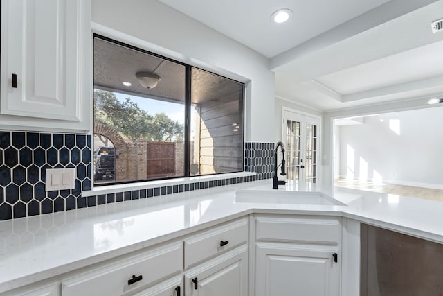 kitchen featuring sink, white cabinetry, french doors, and tasteful backsplash