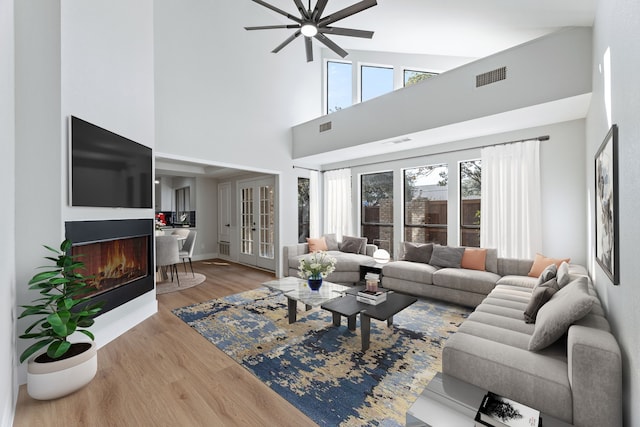 living room with hardwood / wood-style flooring, high vaulted ceiling, and ceiling fan