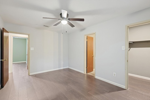 unfurnished bedroom featuring hardwood / wood-style floors, ceiling fan, a closet, and a spacious closet