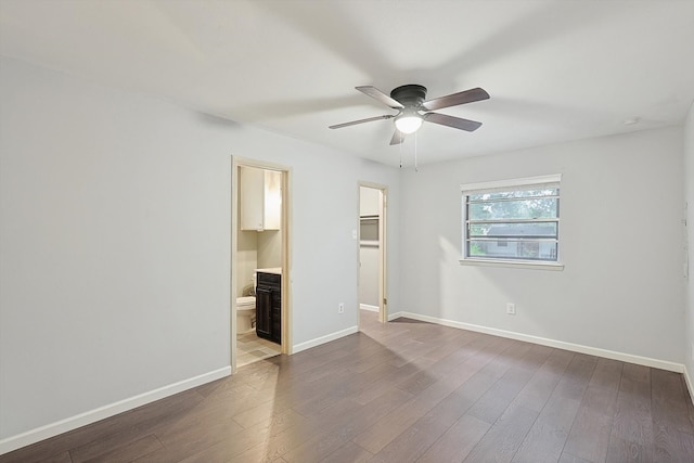 unfurnished bedroom featuring connected bathroom, a spacious closet, hardwood / wood-style flooring, and ceiling fan