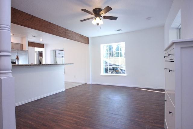 unfurnished living room with beamed ceiling, ceiling fan, and dark hardwood / wood-style flooring