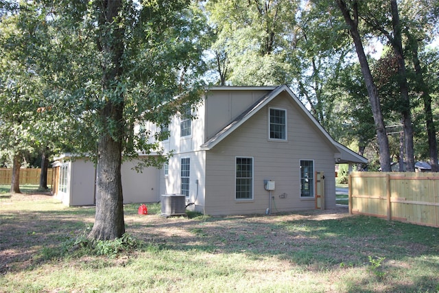 back of house featuring cooling unit and a lawn