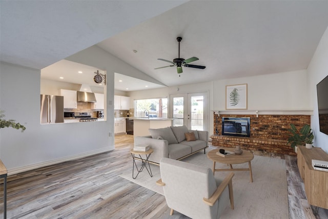 living room with french doors, vaulted ceiling, ceiling fan, sink, and light hardwood / wood-style floors