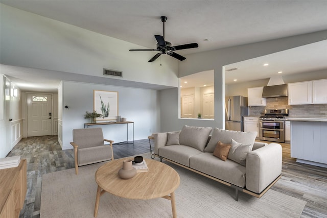 living room with ceiling fan, light hardwood / wood-style floors, and lofted ceiling