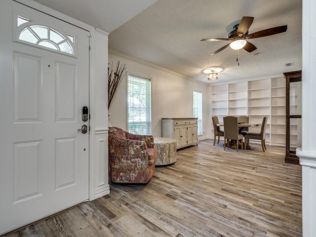 foyer with ceiling fan, light hardwood / wood-style floors, and ornamental molding