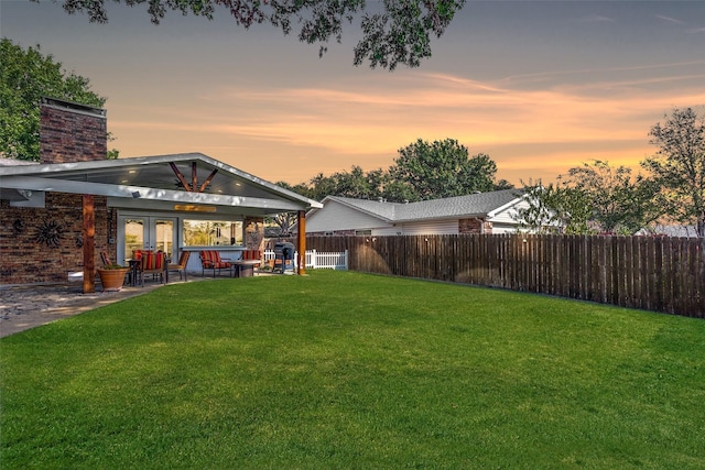 yard at dusk featuring a patio area and french doors